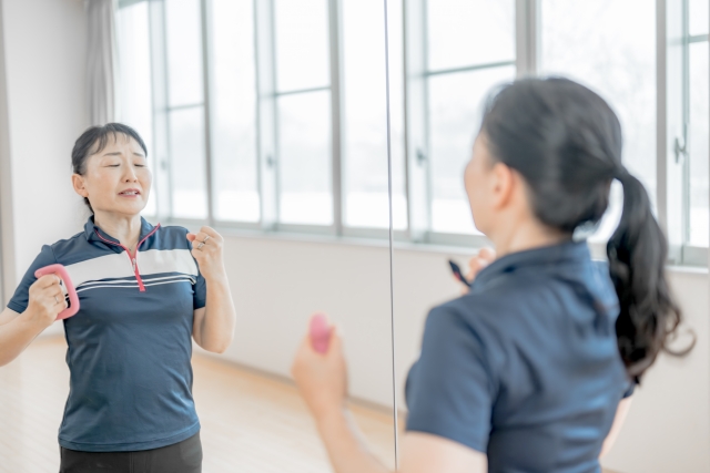 健康維持のために小さなダンベルを使って運動する中年女性。
