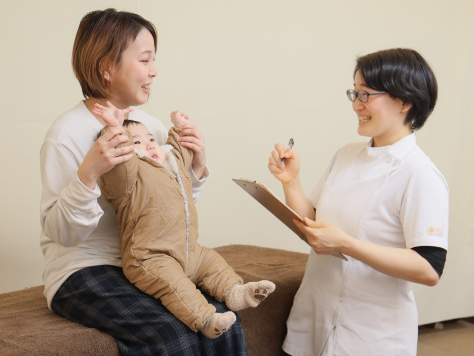 赤ちゃんを抱っこしながらスタッフと笑顔でカウンセリングを受けるお母さん