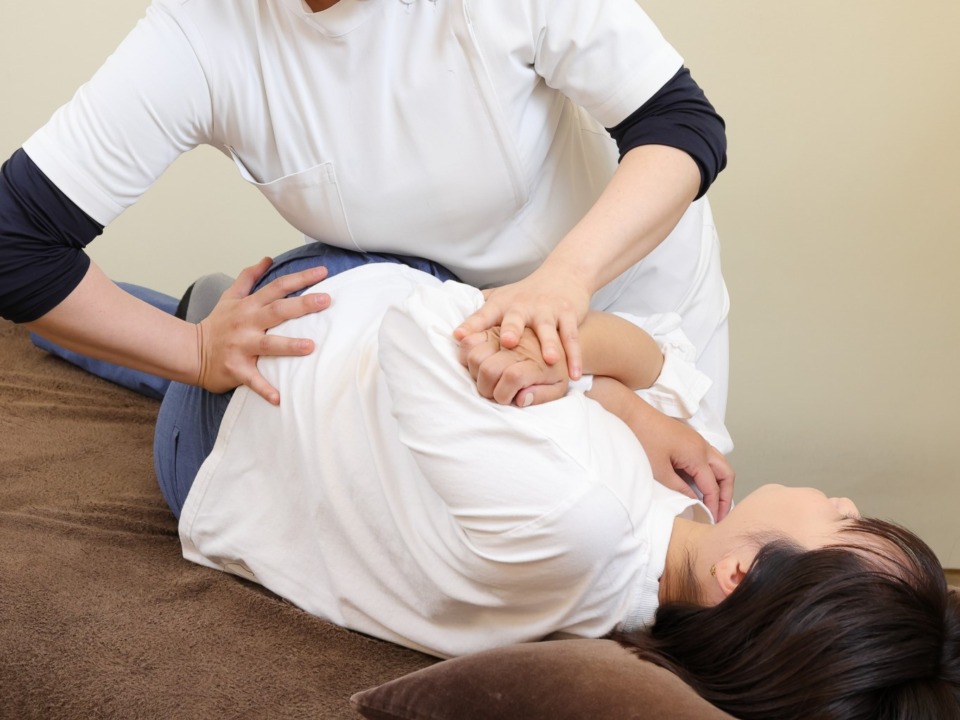 横向きで腰・背中の調整を受ける女性
