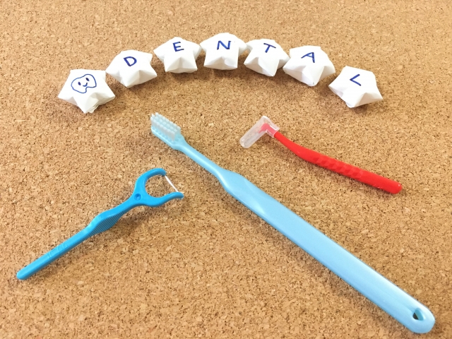 歯ブラシやフロスなどの歯磨き道具とDENTALの文字が並ぶ写真